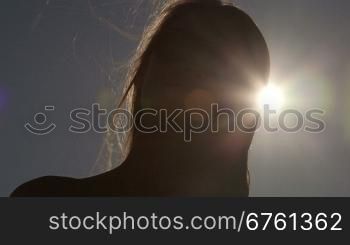 Smiling girl face in sunglasses against the sun looking at camera