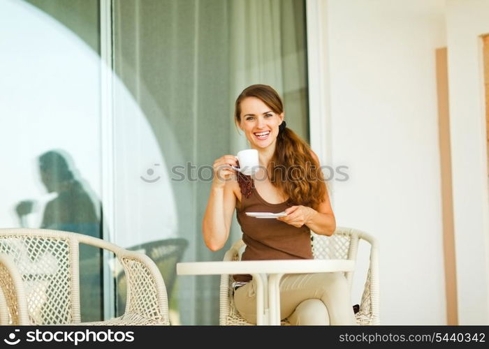 Smiling girl having cup of coffee at terrace