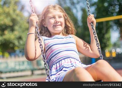 smiling girl having fun on a swing in the playground