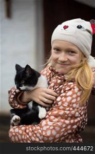 smiling girl holding a cat at her hands
