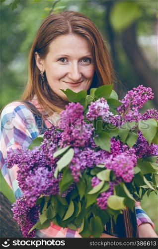 smiling girl holding a huge bouquet of lilac in their hands