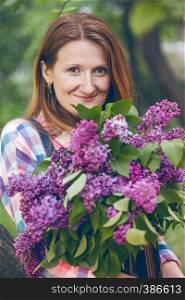 smiling girl holding a huge bouquet of lilac in their hands