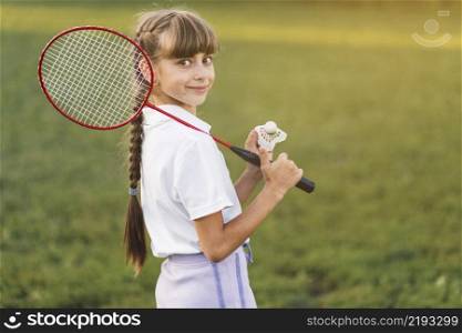 smiling girl holding badminton her shoulder shuttlecock