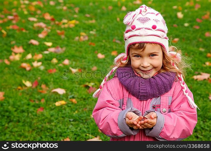 smiling girl holds a chestnut in autumn park