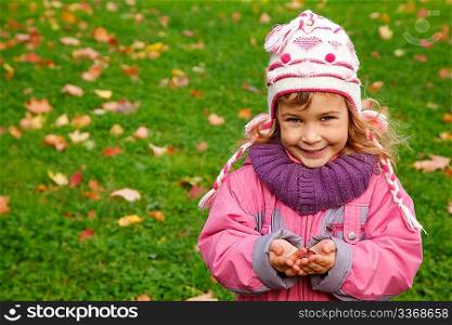 smiling girl holds a chestnut in autumn park