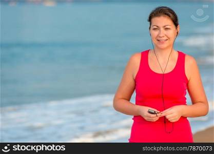 smiling girl in headphones on the background of the sea