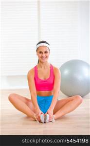 Smiling girl in sportswear sitting in yoga pose at living room&#xA;