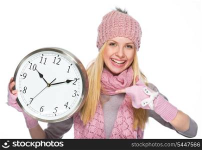 Smiling girl in winter clothes pointing on clock