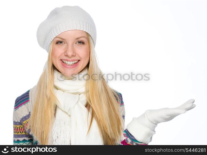 Smiling girl in winter clothes presenting something on empty hand