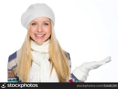 Smiling girl in winter clothes presenting something on empty hand