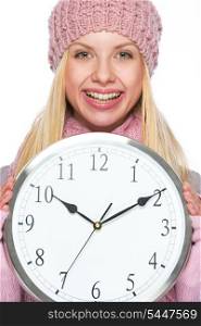 Smiling girl in winter clothes showing clock