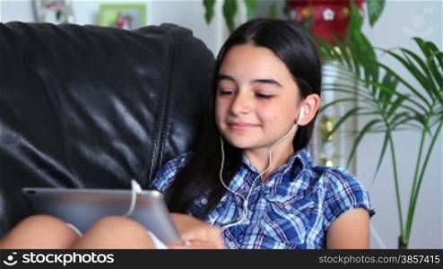 Smiling girl listening to music, holding a tablet pc in hands