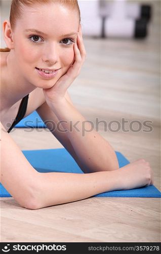 Smiling girl lying on fitness mat