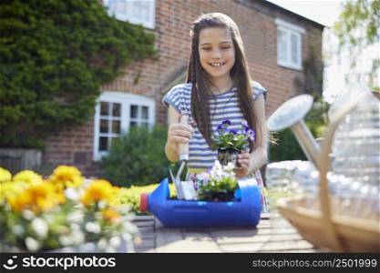 Smiling Girl Making Recycled Plant Holder From Plastic Bottle Packaging Waste In Garden At Home
