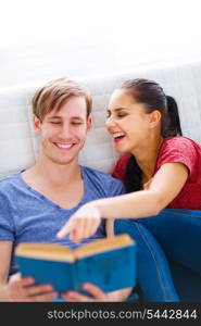 Smiling girl showing something her boyfriend by pointing in book &#xA;
