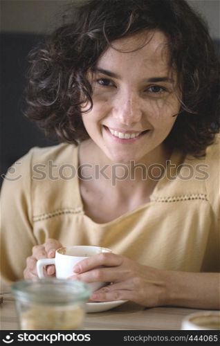 smiling girl sitting at a table in a cafe