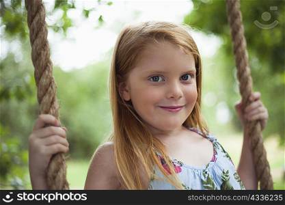 Smiling girl sitting in tree swing