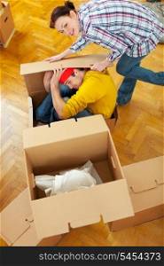 Smiling girl trying to pack boyfriend in cardboard box