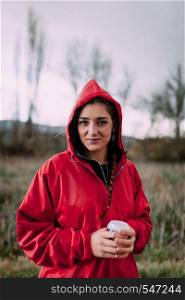 Smiling girl wearing a red raincoat on the field