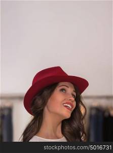Smiling girl wearing cute red hat at store looking upwards coquettishly