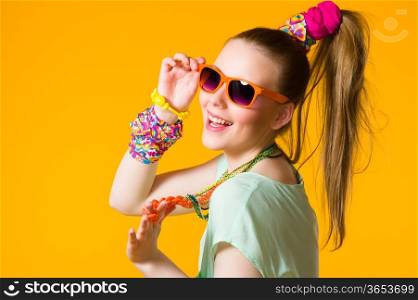 Smiling girl with colorful clothes wearing sunglasses, yellow background