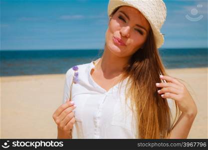 Smiling girl with flower on beach. Holidays and vacation. Lovely cute woman tourist holding little flower on sunny beach. Young girl enjoy her free time on seaside.