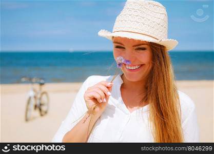 Smiling girl with flower on beach. Holidays and vacation. Lovely cute woman tourist holding little flower on sunny beach. Young girl enjoy her free time on seaside.