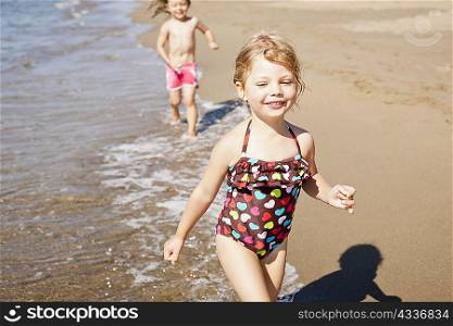Smiling girls playing in waves on beach