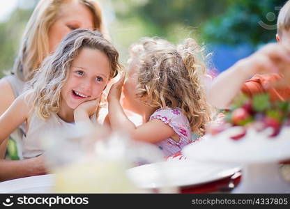 Smiling girls whispering outdoors