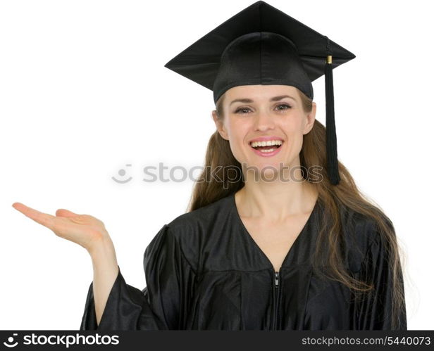 Smiling graduation student girl showing something on empty hand