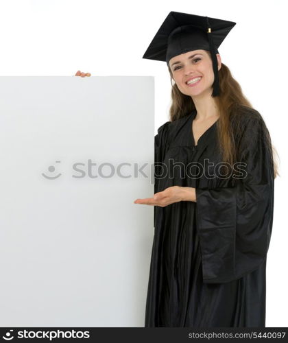 Smiling graduation student woman showing on blank billboard