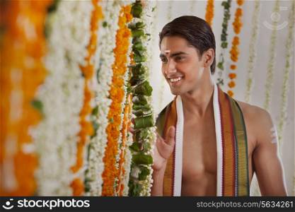 Smiling groom looking through garlands