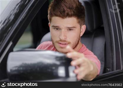 smiling guy fixing the rear view mirror of car