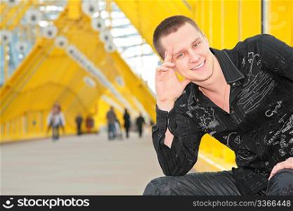 smiling guy sits on yellow footbridge