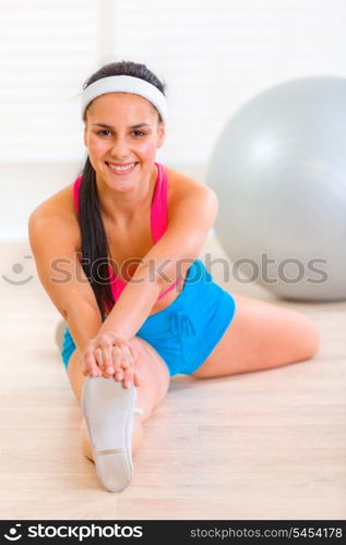 Smiling gymnastic young girl doing stretching exercises at living room&#xA;