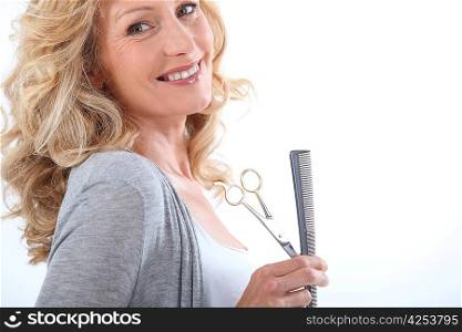Smiling hairdresser with comb and scissors
