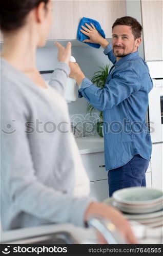 smiling handsome couple cleaning the kitchen