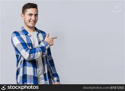 Smiling handsome man recommending something with his fingers. Caucasian handsome guy pointing his finger at a blank space, Smiling teenager pointing fingers to the side