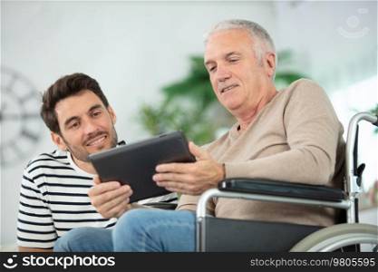 smiling handsome man showing tablet to his eldery father