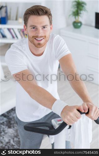 smiling handsome man training on exercise bike