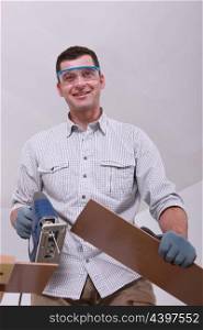Smiling handyman cutting planks