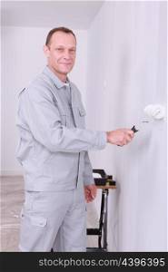 Smiling handyman painting a room white