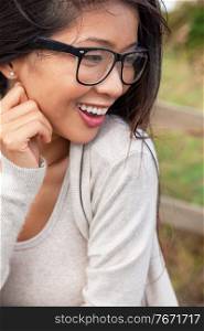 Smiling happy beautiful young Asian Chinese woman or girl wearing glasses outside
