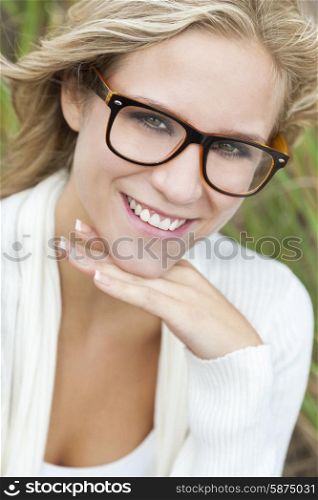 Smiling happy beautiful young blond blonde woman or girl wearing geek glasses outside