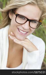 Smiling happy beautiful young blond blonde woman or girl wearing geek glasses outside