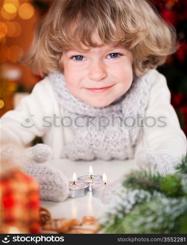 Smiling happy child with Christmas candles and decorations. Focus on candles