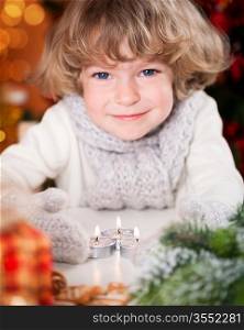 Smiling happy child with Christmas candles and decorations. Focus on candles