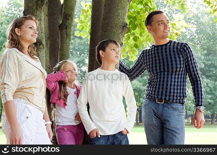 smiling happy family of four looking aside outdoors