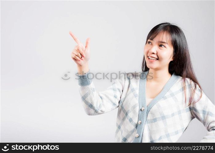 Smiling happy woman pointing finger out space, Portrait Asian beautiful young female point into empty looking to side away, studio shot isolated on white background with copy space