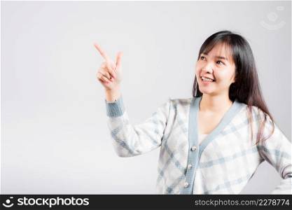 Smiling happy woman pointing finger out space, Portrait Asian beautiful young female point into empty looking to side away, studio shot isolated on white background with copy space
